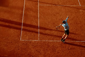 Man playing tennis in orange court